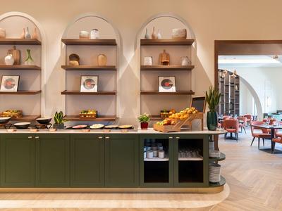 Moderne buffetruimte met groene toonbank en wandplanken in een hotelrestaurant.