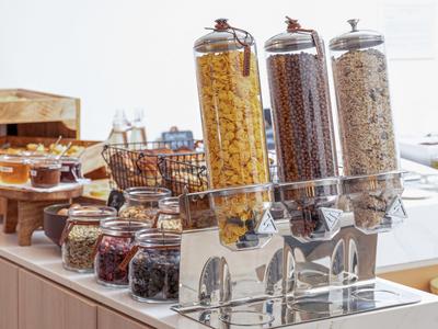 Frühstücksbuffet mit Getreide- und Nuss-Spendern sowie Marmeladen im Hotel.