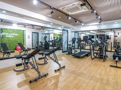 Moderner Fitnessraum im Hotel mit verschiedenen Trainingsgeräten und Holzfußboden.