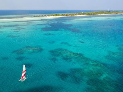 Segelboot auf klarem, türkisfarbenem Wasser vor einer sandigen Insel