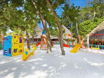Bunter Kinderspielplatz mit Schaukeln und Rutschen im Sand unter Bäumen.