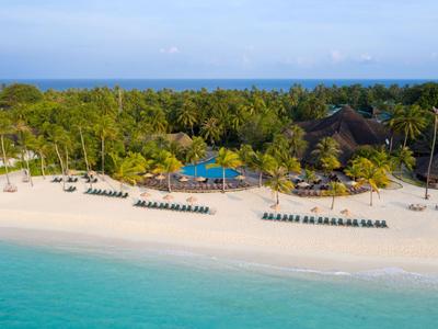 Strand mit Liegestühlen und Palmen an einem tropischen Hotelresort am türkisblauen Meer.