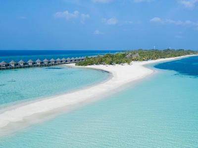 Sandbank umgeben von türkisblauem Wasser mit kleinen Hütten am Rand bei sonnigem Himmel