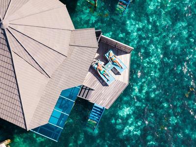 Luftaufnahme von über Wasser gebauten Bungalows mit Zugang zu klarem, türkisfarbenem Wasser.
