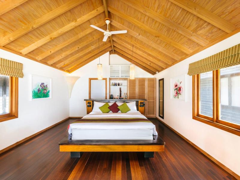 Helles Schlafzimmer mit Holzboden, doppeltem Himmelbett und Fenstern auf beiden Seiten.