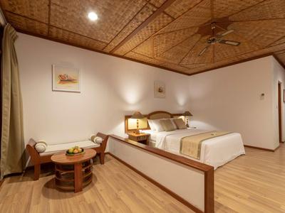 Gemütliches Schlafzimmer mit Holzboden, dekorativer Holzdecke, Doppelbett und gemütlicher Sitzgruppe.
