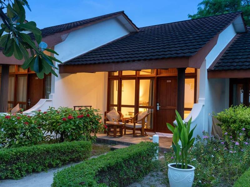 Gemütliches Haus mit eingezäuntem Garten und heller Beleuchtung am Abend.