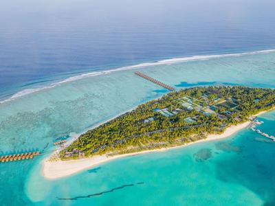 Luftaufnahme einer tropischen Insel mit Strand, Wasserbungalows und klarem türkisfarbenem Meer.