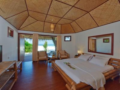 Gemütliches Schlafzimmer mit Holzmöbeln, Doppelbett, Stühlen und Blick in einen Garten.
