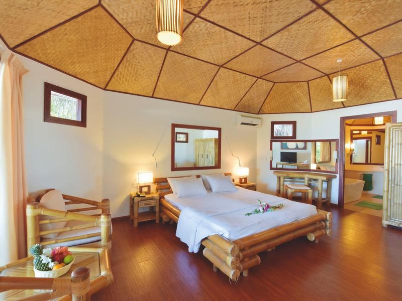 Gemütliches Hotelzimmer mit Holzmöbeln und Doppelbett, warm beleuchtet.