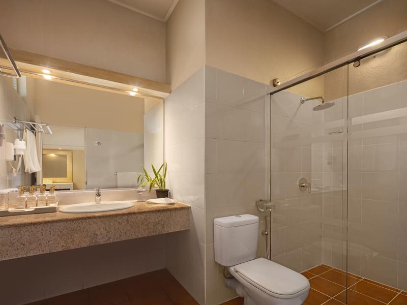 Modernes Badezimmer mit Waschbecken, Toilette, Glas-Duschkabine und warmem Licht.