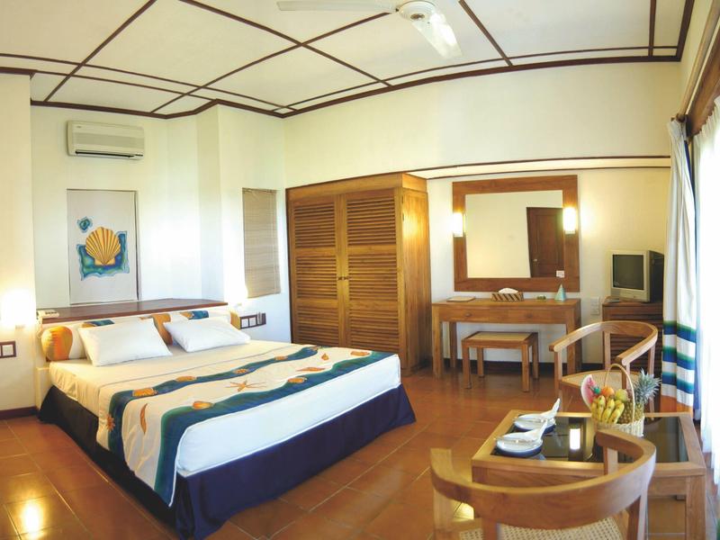 Großes Schlafzimmer mit Doppelbett, Holzmöbeln und hellen Wänden, einladend und ordentlich.