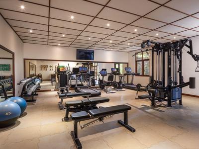 Moderner Fitnessraum mit Hantelbank, Trainingsgeräten, Spiegeln und großem Ball.