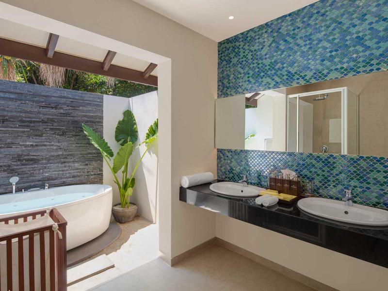 Salle de bain moderne avec baignoire indépendante et doubles vasques à côté d'une grande fenêtre.