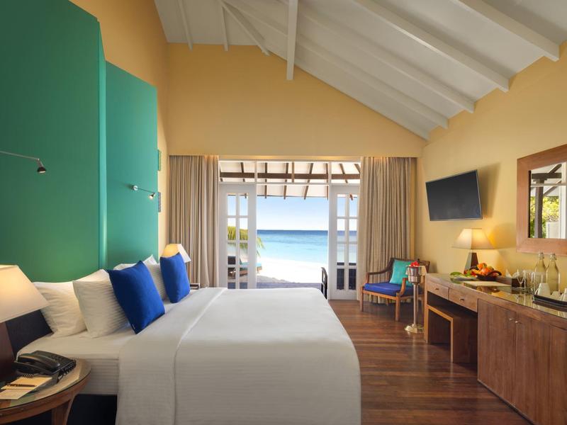 Chambre d'hôtel avec deux lits, accents bleu-vert et vue sur l'océan.