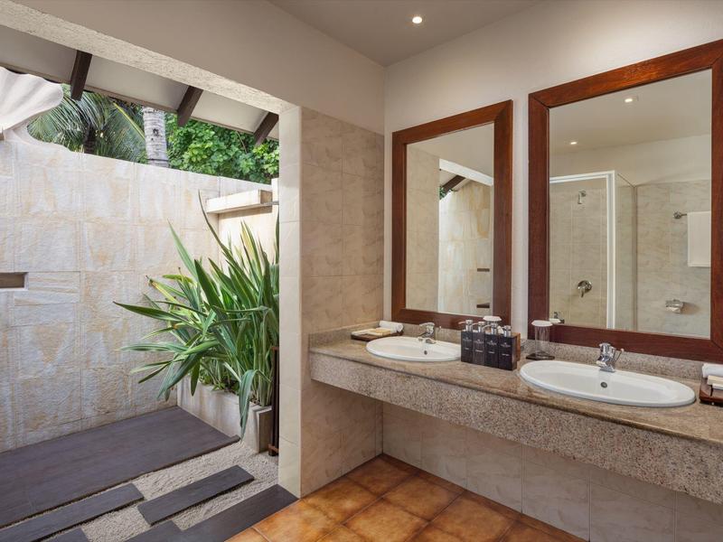 Salle de bain moderne avec double vasque et accès à une douche extérieure privée.