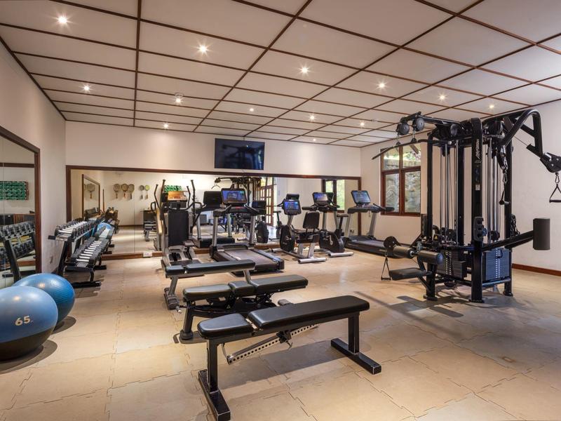 Salle de sport moderne équipée de divers appareils d'exercice et de cardio.