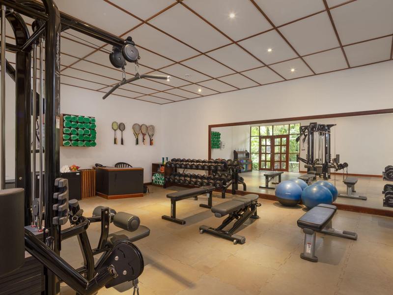 Salle de sport moderne avec divers équipements d'exercice et grandes fenêtres pour la lumière naturelle.