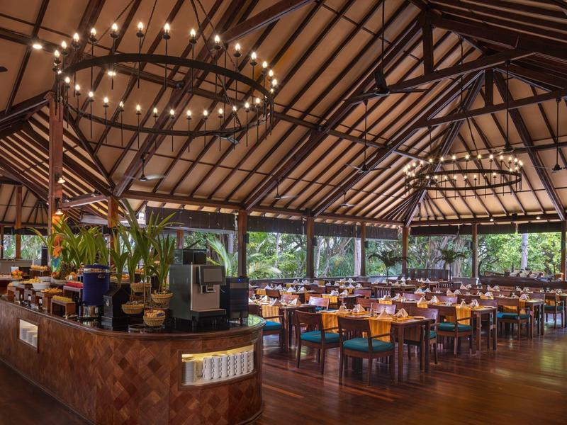 Grand restaurant ouvert avec toit en bois, sièges modernes et plantes d'intérieur.