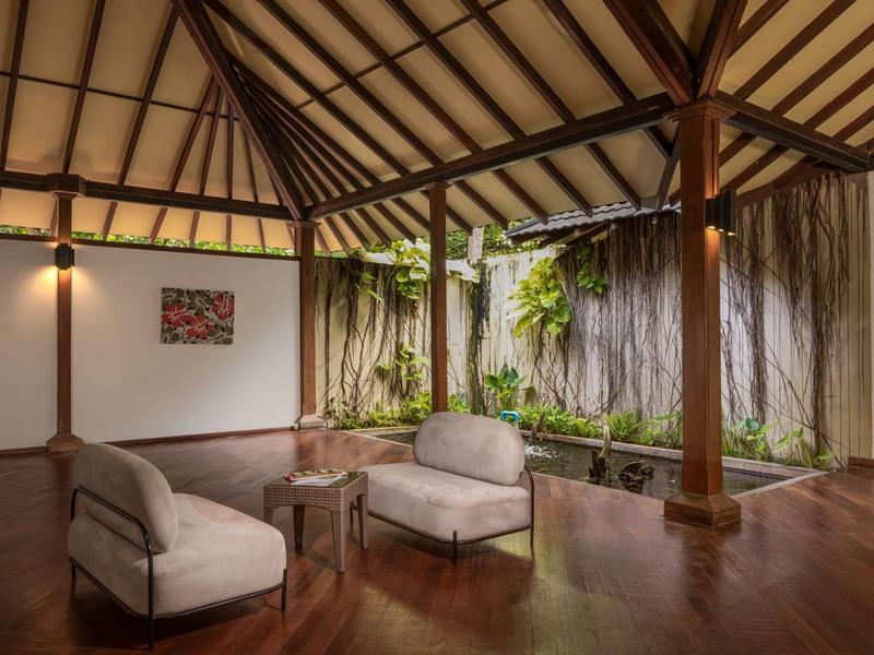 Espace de vie en plein air calme avec parquet et mur végétal dans un hôtel tropical.