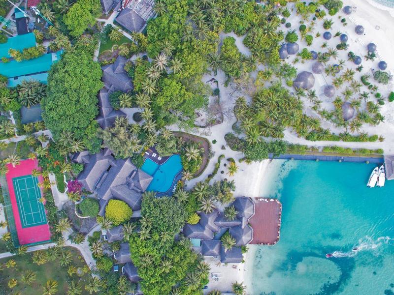 Luftaufnahme einer tropischen Insel mit weißem Sandstrand, grünen Palmen und türkisblauem Meer.