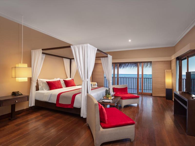 Luxuriöses Schlafzimmer mit Himmelbett, Holzboden, roten Akzenten und Balkon mit Meerblick.