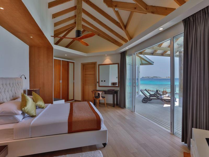 Luxuriöses Schlafzimmer mit Holzbalkendecke, großem Bett und Meerblick durch bodentiefe Fenster.