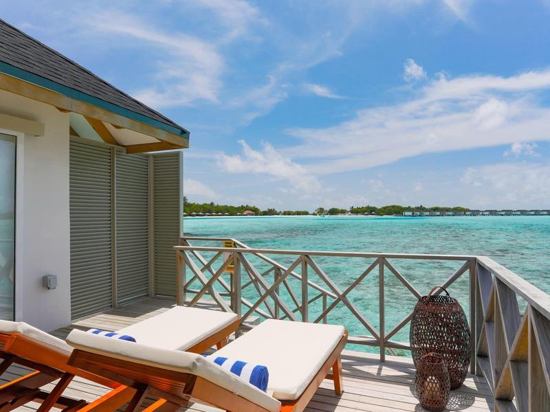 Terrassen mit zwei Liegestühlen und Blick auf türkisfarbenes Meer unter blauem Himmel.