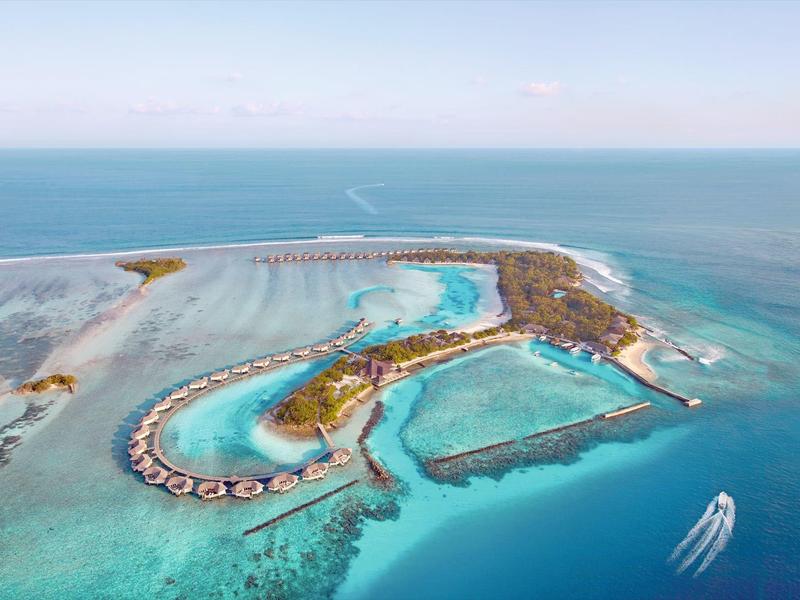 Tropische Insel mit türkisfarbenem Wasser, Strandbungalows und umliegendem Korallenriff.