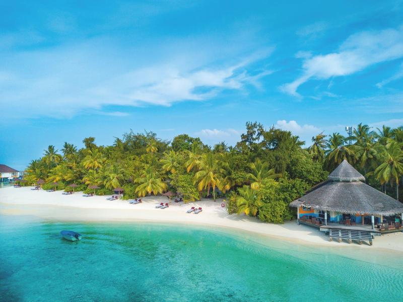 Tropical island with white sandy beach, turquoise water, and a wooden pavilion at the edge.