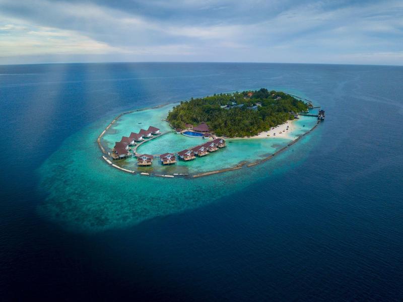Aerial view of a small tropical island with overwater bungalows and white sandy beach.