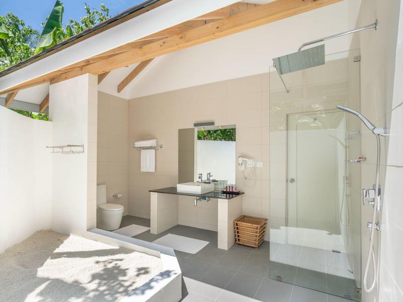 Bright, modern outdoor bathroom with shower, toilet, sink, and door leading outside.
