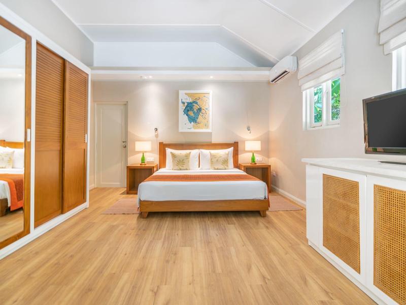 Bright, modern hotel room with double bed, wooden floor, and wardrobe with mirrored doors.