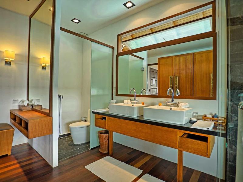 Moderní koupelna s dvojitým umyvadlem, dřevěnými skříňkami a velkým zrcadlem.