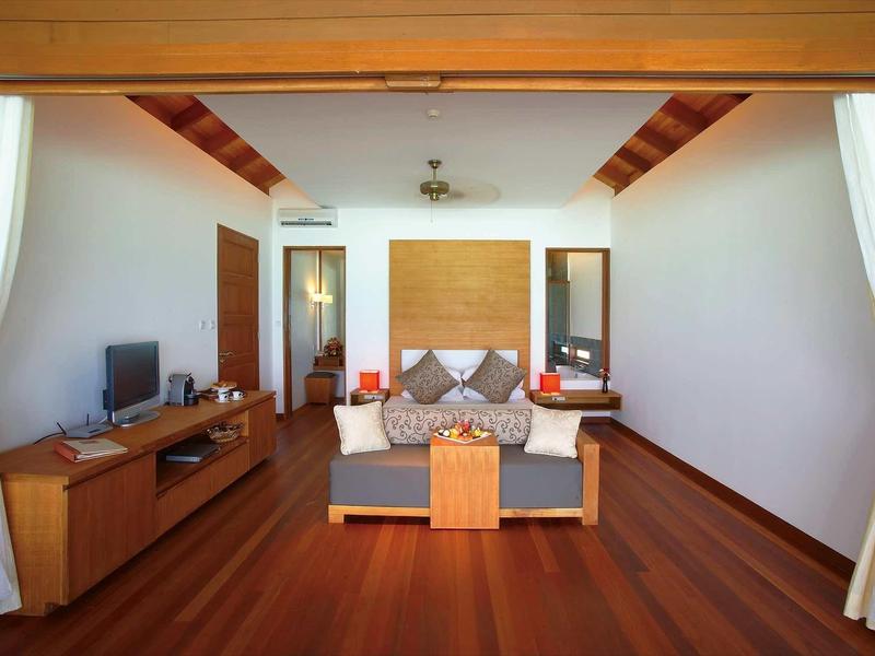 Elegantní hotelový pokoj s manželskou postelí, dřevěnou podlahou a televizí na komodě