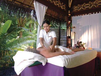 Patio coperto con muro di pietra e cascata, circondato da piante e decorazioni.