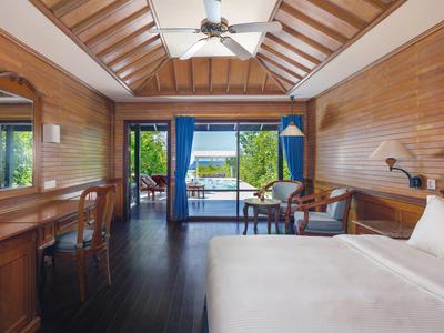 Camera moderna con pannelli in legno, letto king-size, scrivania e vista su balcone e mare.