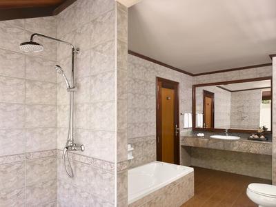 Bagno moderno con doccia, vasca da bagno e doppio lavabo in una camera d'hotel.