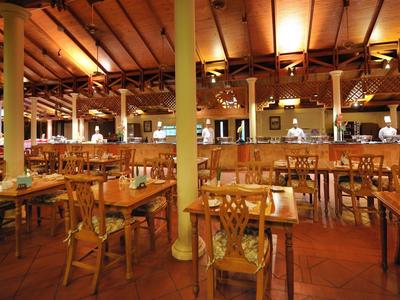 Ristorante spazioso con sedie e tavoli in legno, illuminazione calda.