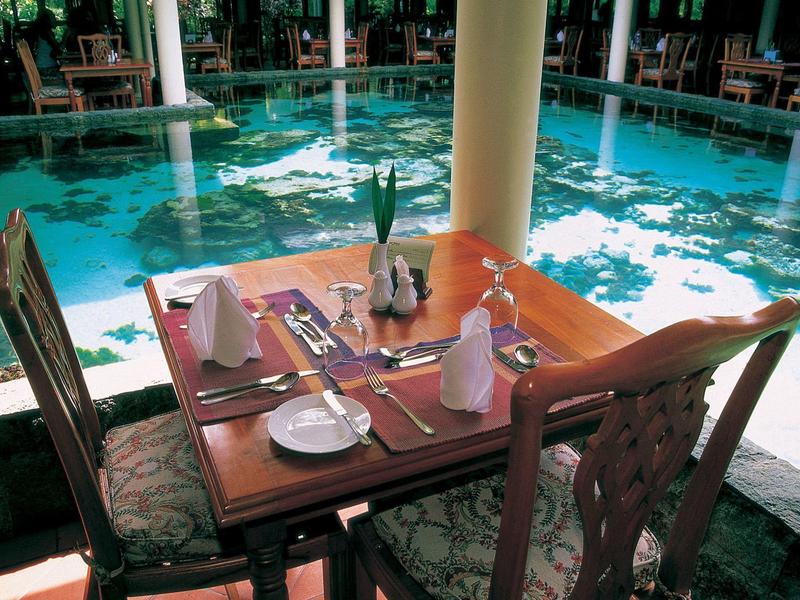 Un tavolo apparecchiato con quattro sedie accanto a una piscina in un ristorante dell'hotel.