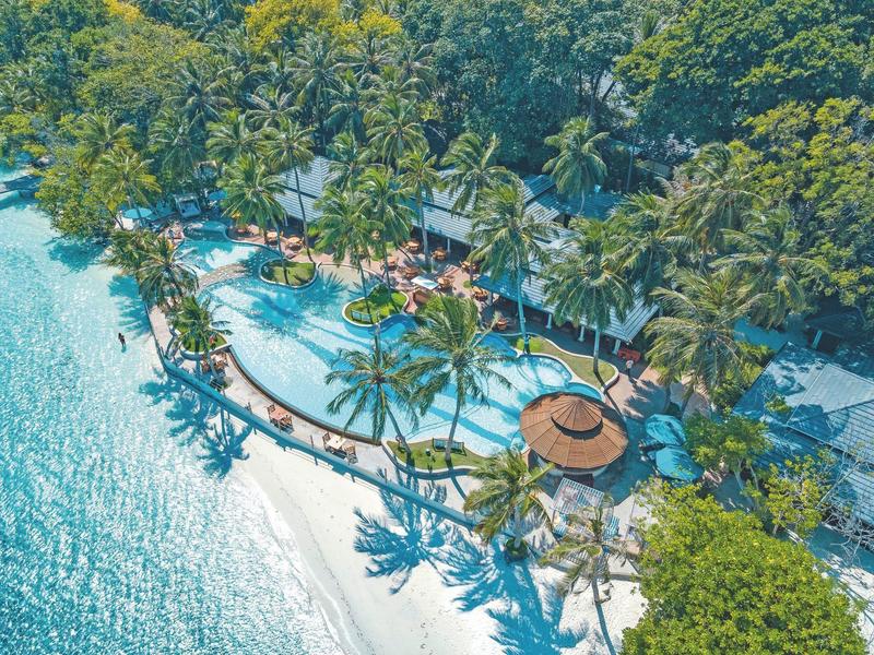 Vista aerea di un resort tropicale con piscina, palme e accesso diretto alla spiaggia.