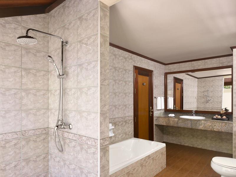 Bagno moderno con doccia, vasca da bagno e doppio lavabo in una camera d'hotel.