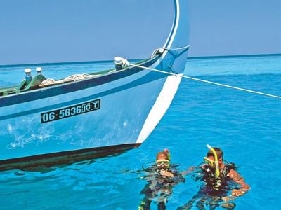 Zwei Schnorchler im klaren blauen Wasser neben einem weißen Boot mit Flaggen.