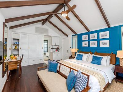 Geräumiges Schlafzimmer mit Holzbalkendecke, blauer Akzentwand und modernem Mobiliar.