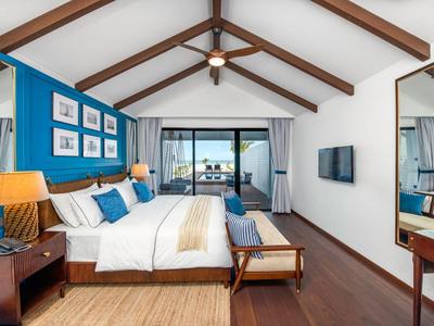 Modernes Hotelzimmer mit Doppelbett, Holzbalkendecke und Blick auf Balkon und Meer.