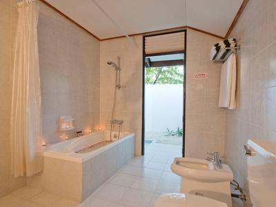 Schlichtes Badezimmer mit Badewanne, Dusche, Bidet und Zugang zu einem Außenbereich.