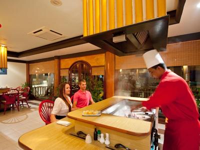 Koch in roter Uniform bereitet Speisen an einem Teppanyaki-Grill in einem Restaurant zu