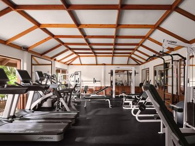 Modernes Fitnessstudio mit Laufbändern, Kraftgeräten und Holzbalkendecke.