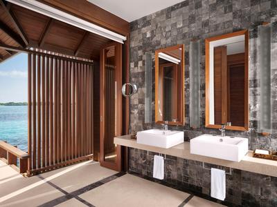 Modernes Badezimmer mit zwei weißen Waschbecken, Holzspiegeln und Blick auf Wasser durch Holzjalousien.