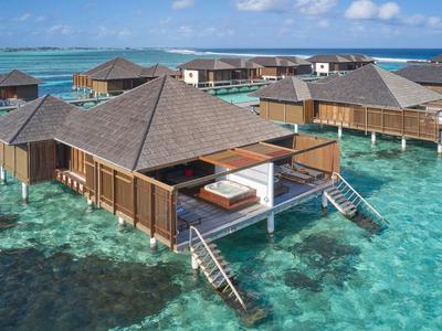 Bungalows auf Pfählen über klarem, türkisfarbenem Wasser mit Treppen und Sonnendecks.